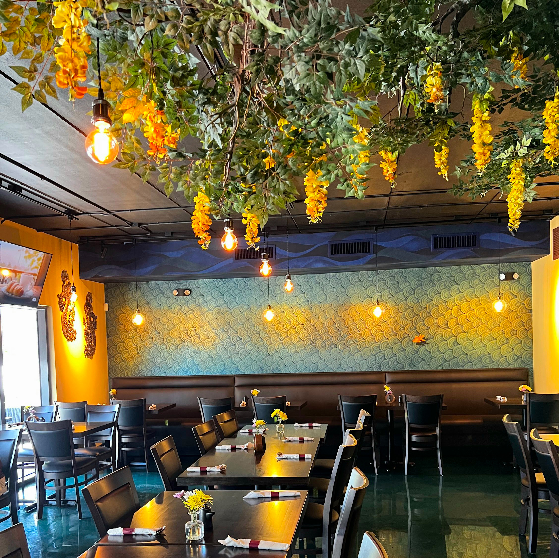 Nour Thai Kitchen dining room with a wisteria canopy, scalloped gold mural, and Thai dragon sconces